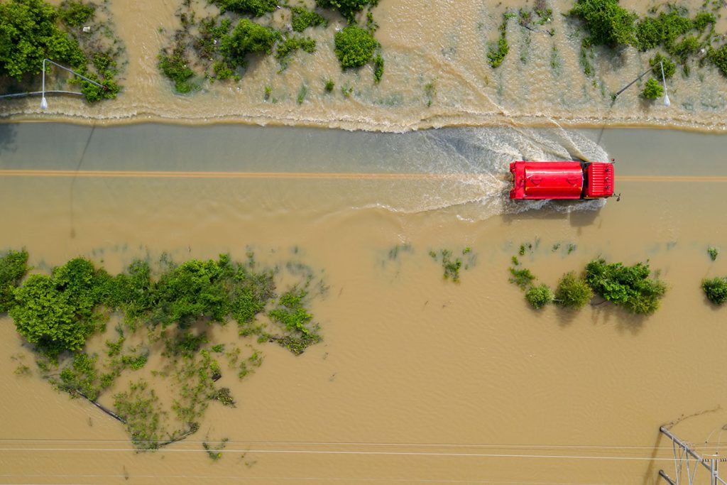 Aerial top view of Flooded the village and Country road with a red car, View from above