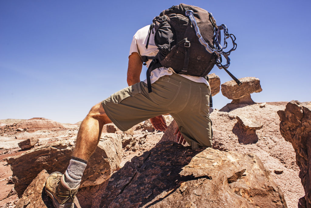 A man climbing a rock dressed in KUHL mens climbing shorts and hiking shirts