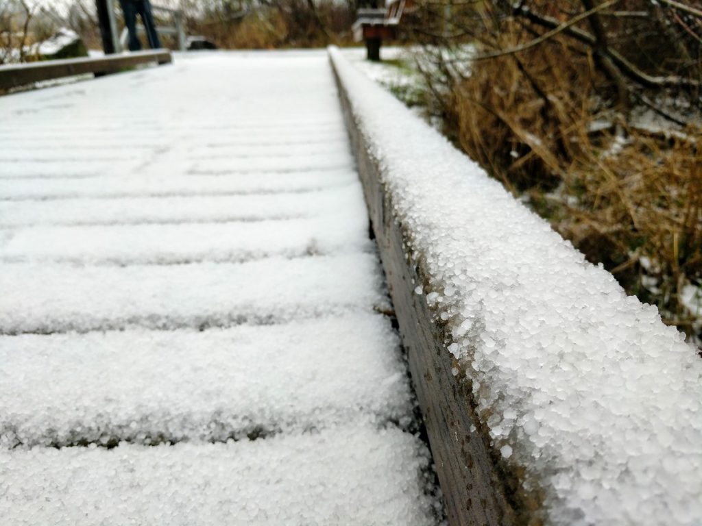 A snow covered edge of a wooden pedestrian bridge