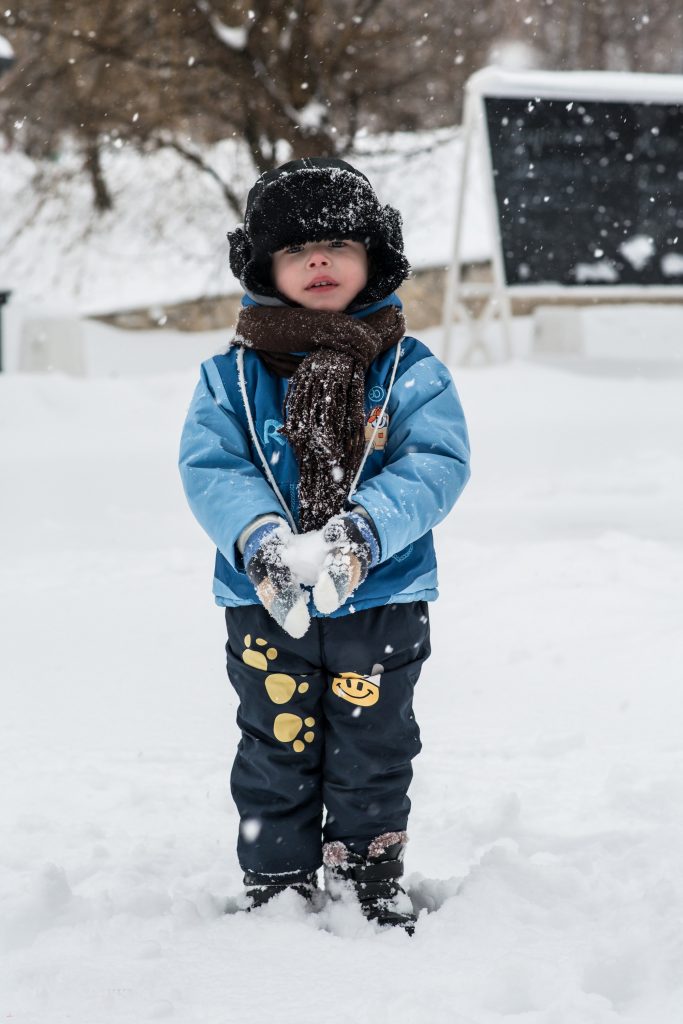 The Magic of Snow: A boy making a snowball in winter, dressed in blue jacket and paw printed pants