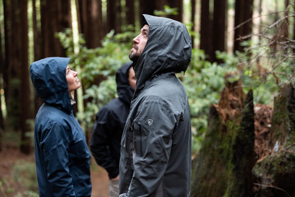 three people in the woods wearing Kuhl jackets
