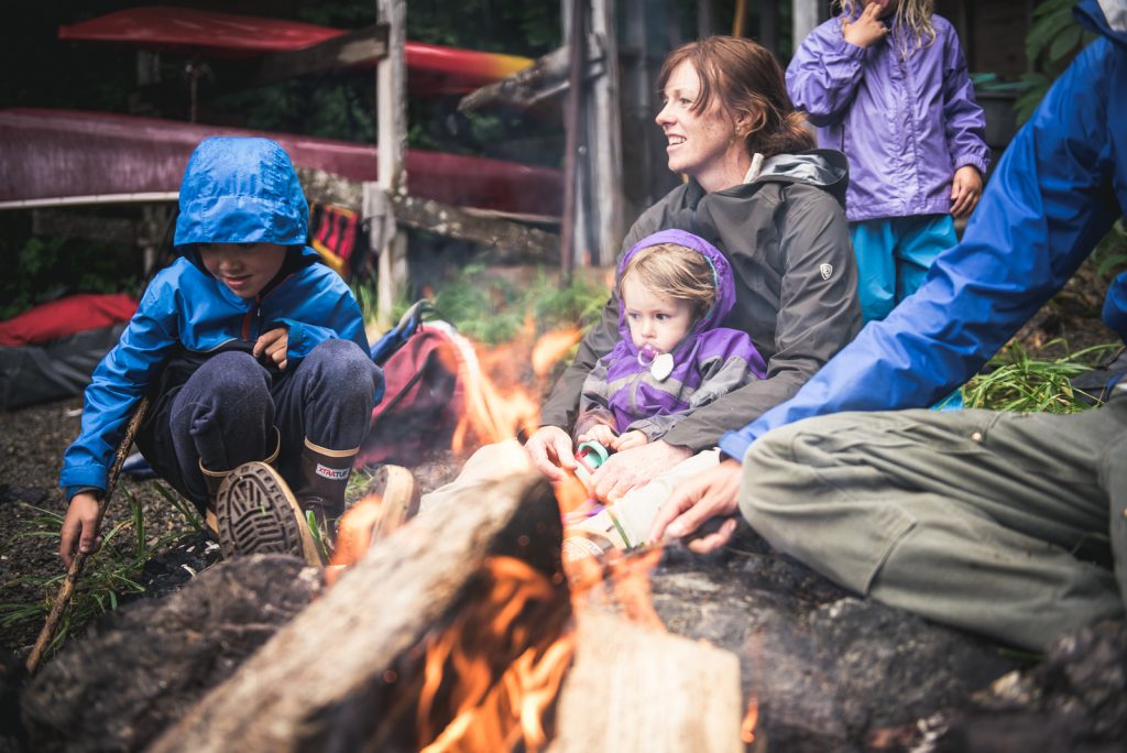 Kid Outdoors - Children and parents around campfire dressed in KUHL clothing