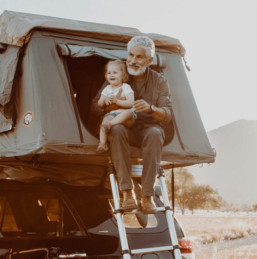 An older man holding a baby in a tent - KUHL clothing