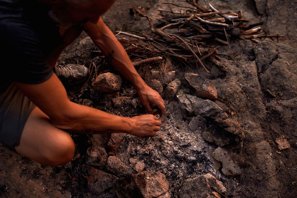Close up shot of male hands making fire in the wild at sunset