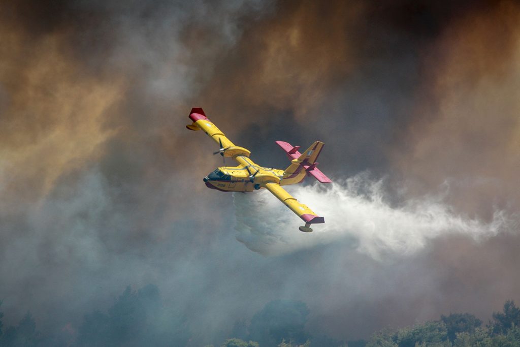 yellow plane flying over wildfire and puting it out