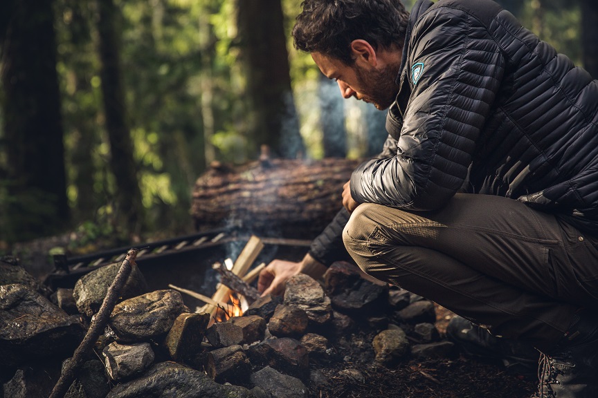 Camping Traditions - Man in KUHL Spyfire Hoody lighting a campfire.