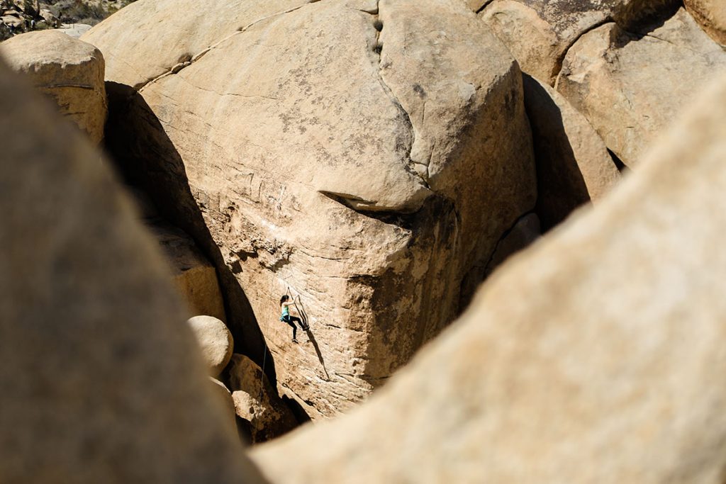 woman climbing on brown rock at daytime