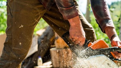 man in brown pants cutting wood with motor saw