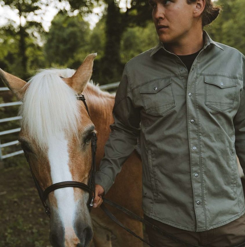 A man in a jacket holding a horse
