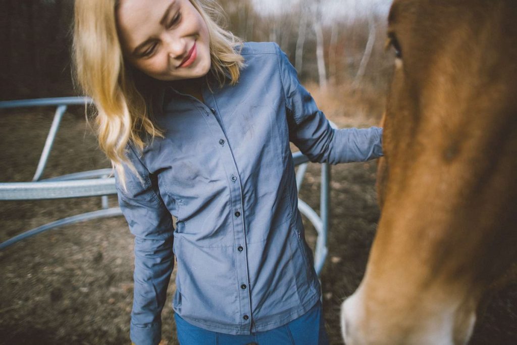 a girl in a blue shirt next to a horse