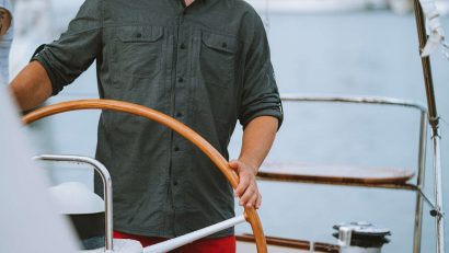 man in dark shirt holding boat wheel