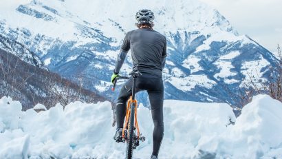 man on bike yellow bike in front of snowy mountain