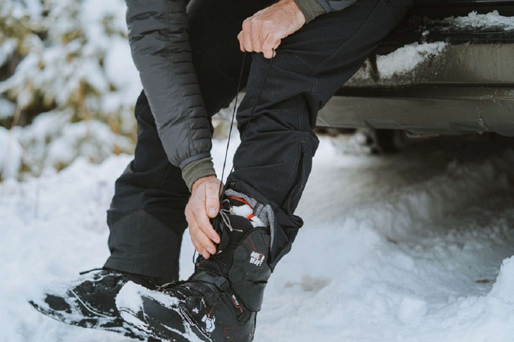man in black pants and black boots on snowy ground