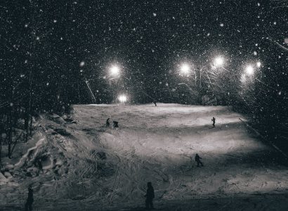 snowy ground with skiers in night with lights around