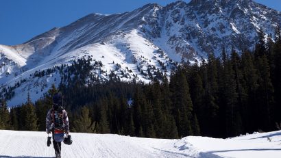person walking on snow road facing mountain at daytime