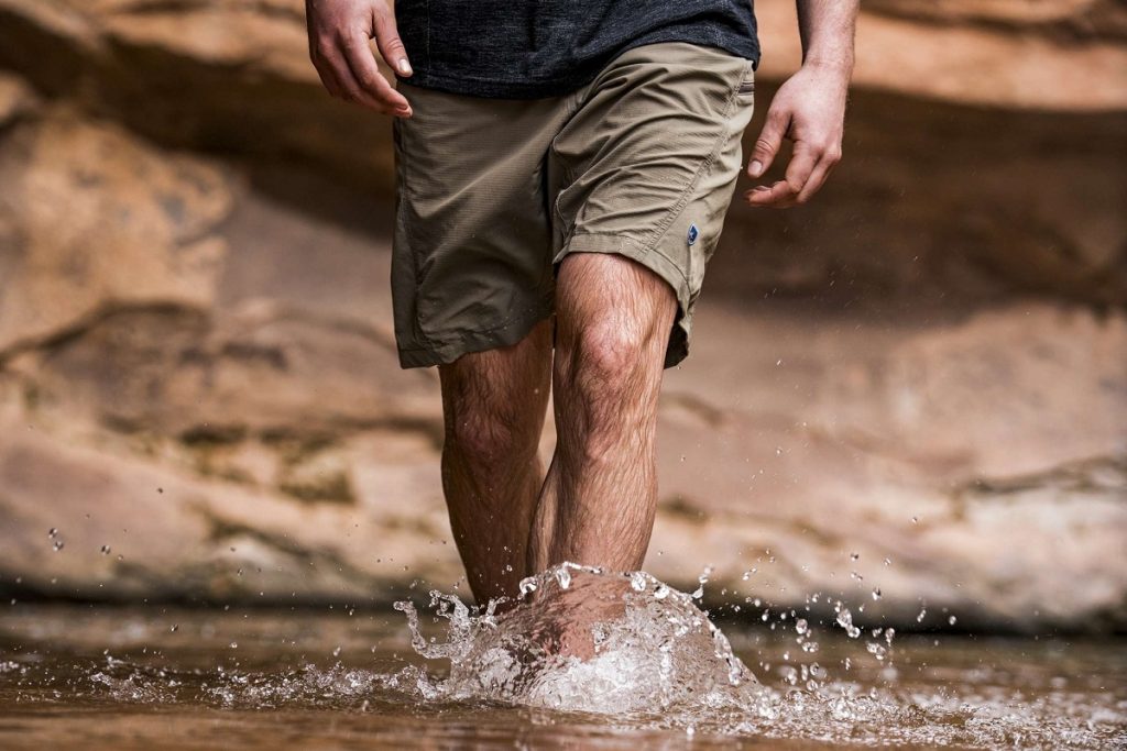 man walking through water in gray shorts