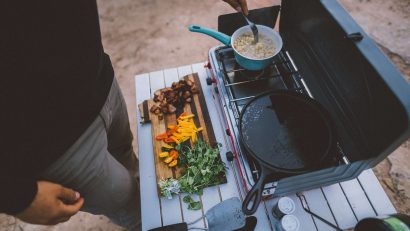 man standing next to a table with camping stove with food pans