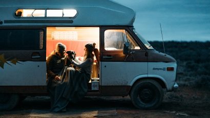 two people in KÜHL clothing RV camping with a dog during nighttime
