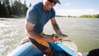 man in KÜHL shorts holding fish on blue raft