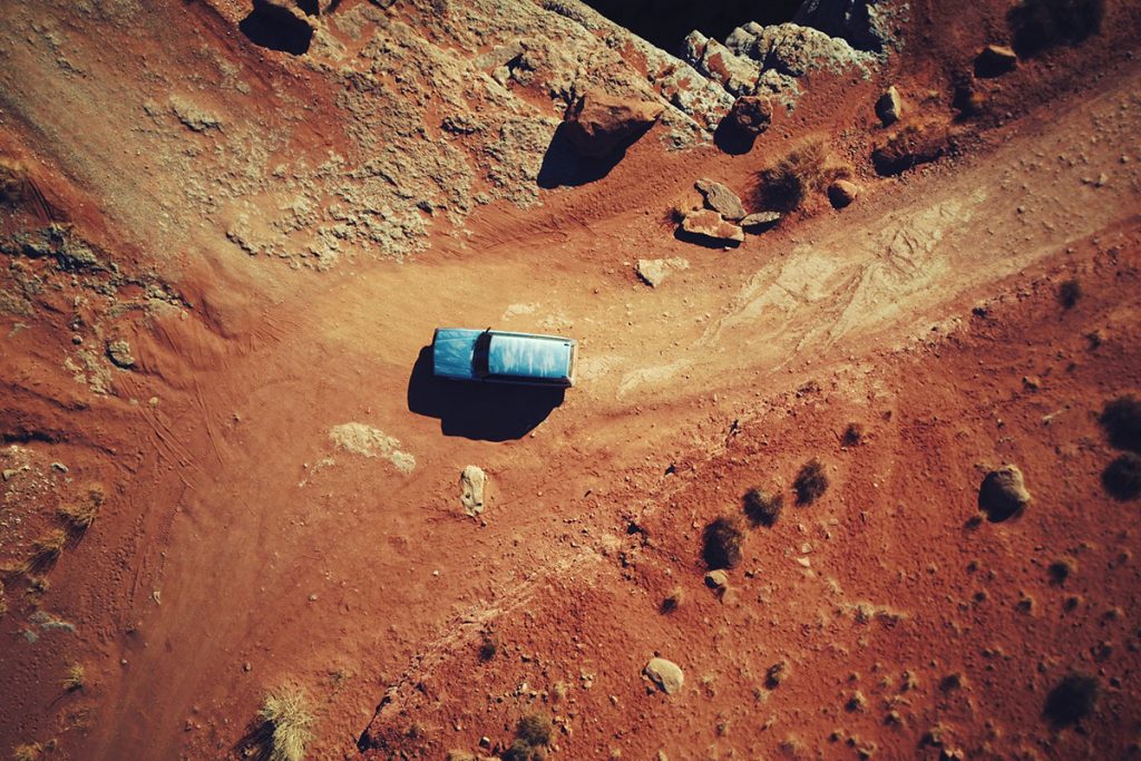 blue car on brown dirt road