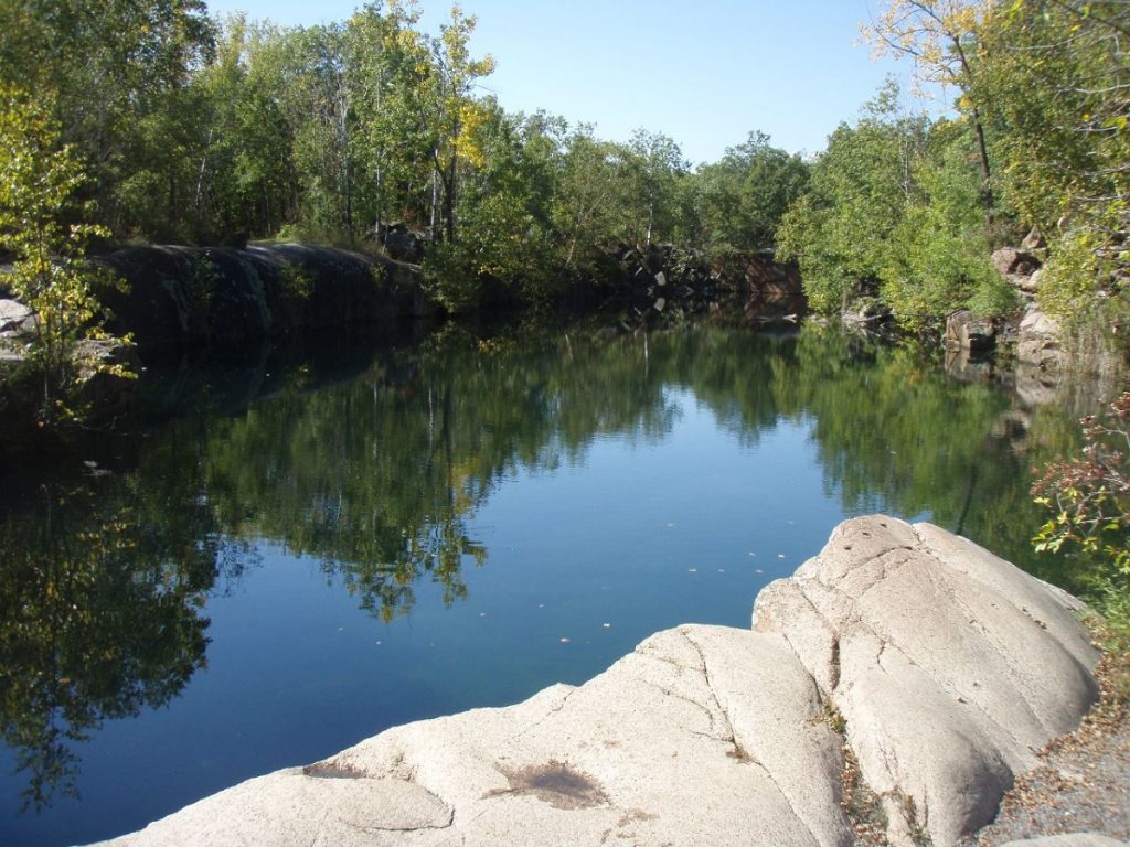 body of water surrounded by green trees and white rock