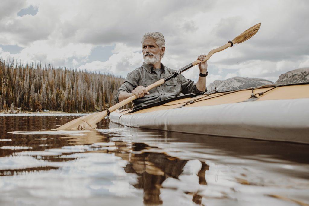 man paddling kayak on body of water