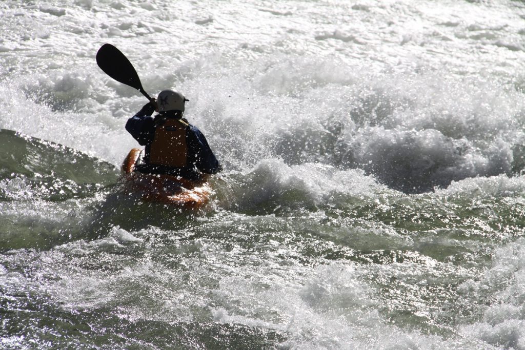 man paddling through white waters