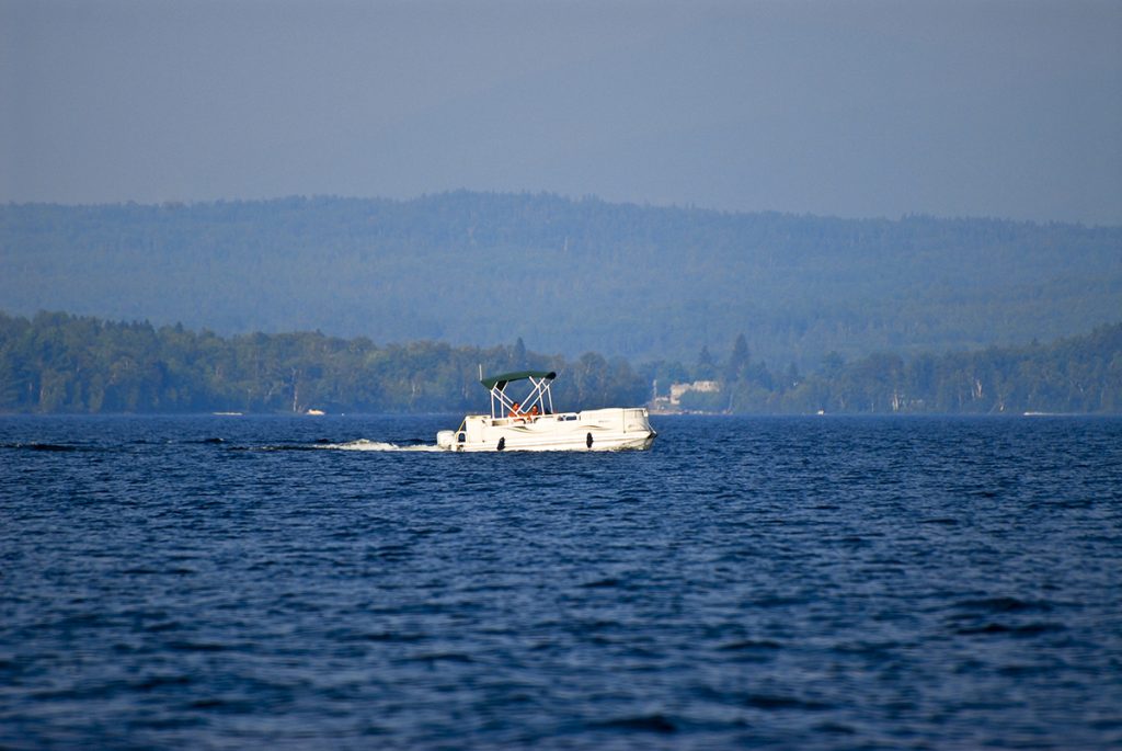 white pontoon boat on blue body of water