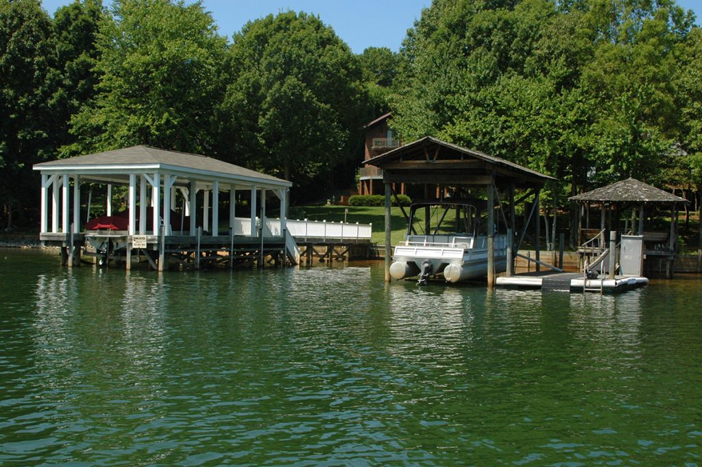 pontoon boat parked on body of water next to lake house
