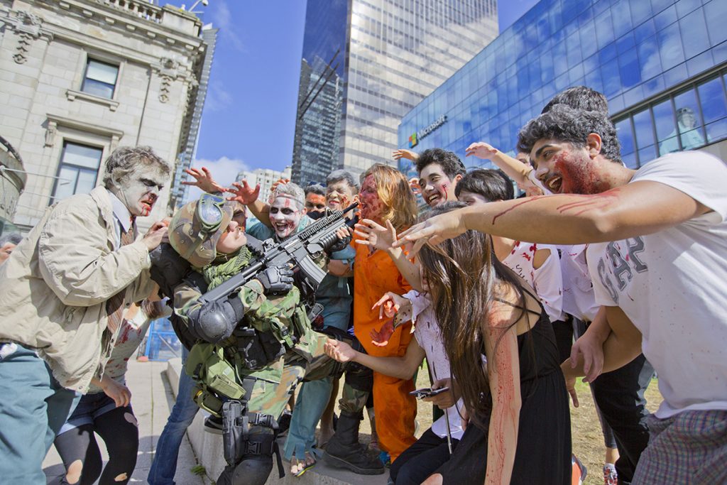 group of people masked in zombies attack man in army uniform