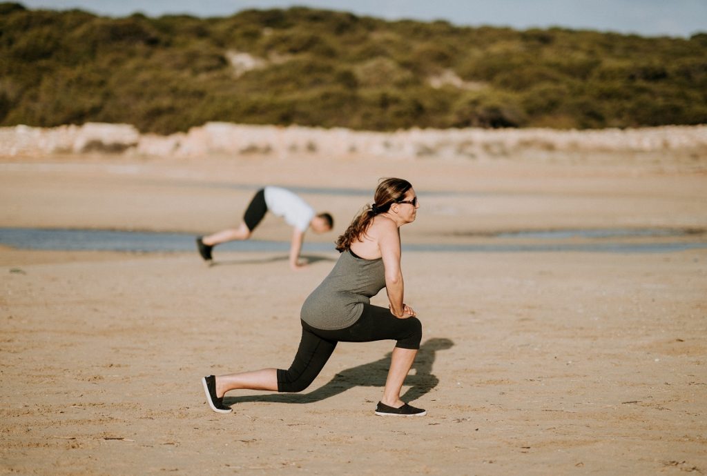 woman doing walking lunges on beach