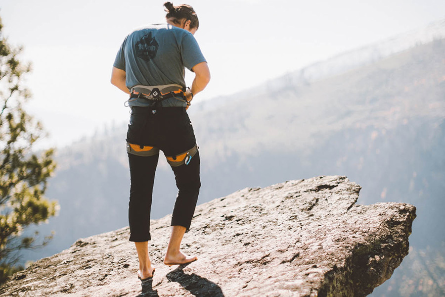 man in KUHL pants standing on cliff during daytime