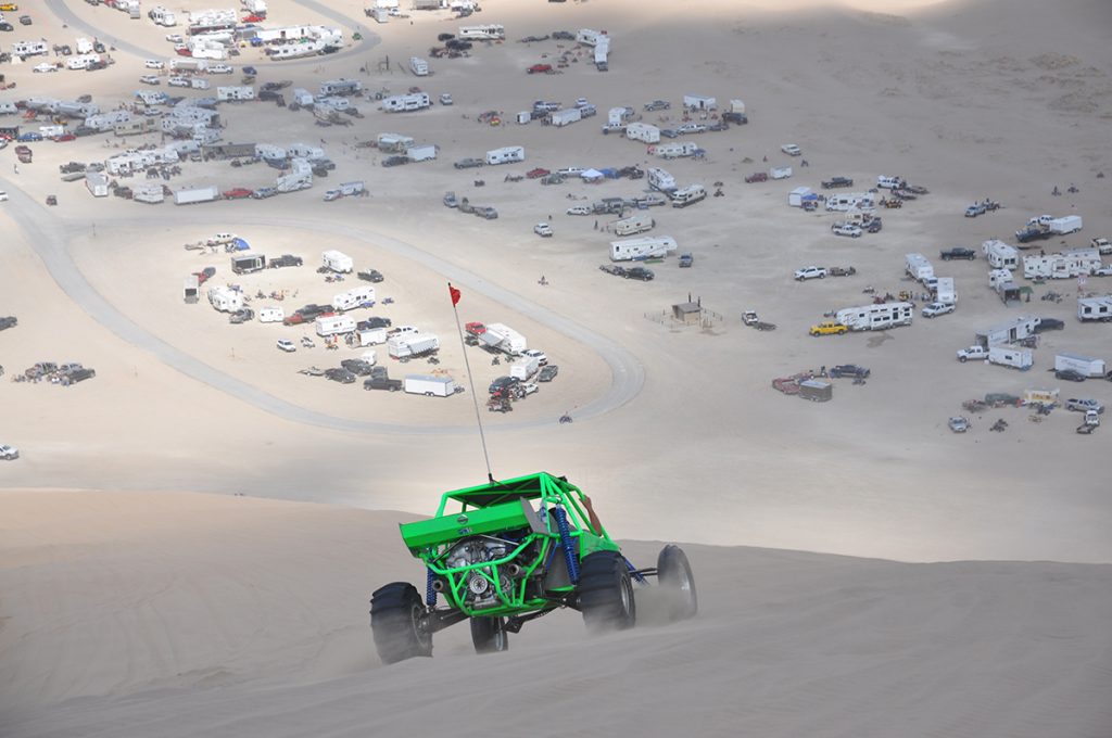 green OHV riding on sand