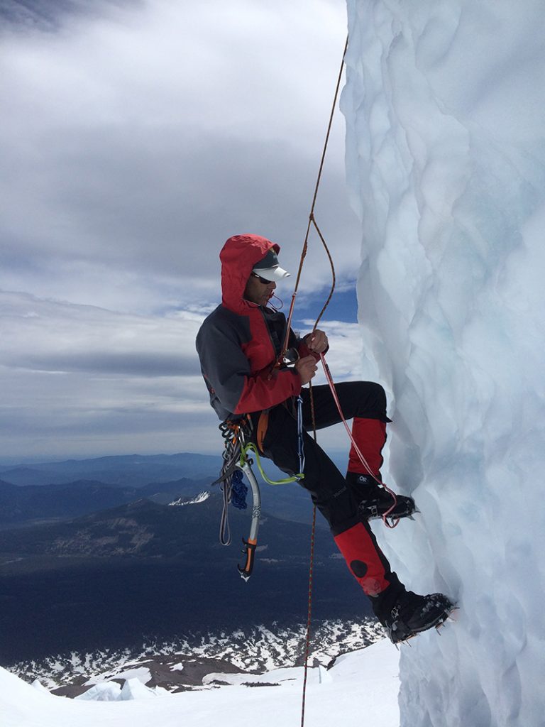 climber in red and black outerwear climbing the ice mountain