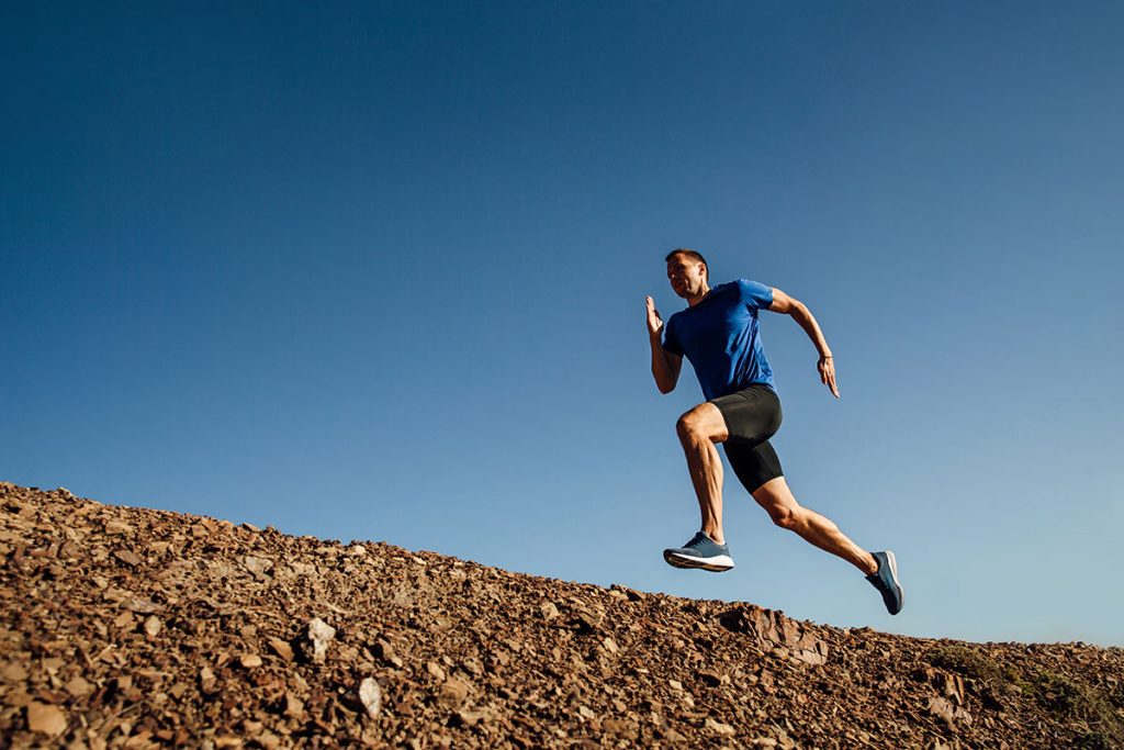 dynamic running uphill athlete runner on background of blue sky