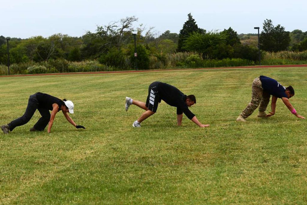 Three people doing Bear Crawl exercise on the grass