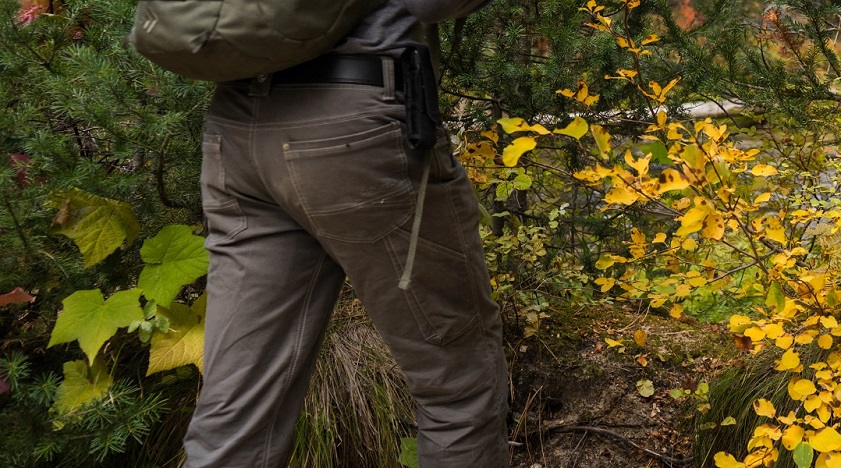 A man hiking between the shrubs, wearing a pair of KUHL quick dry pants