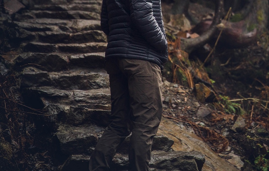 A man standing at the bottom of stone stairs, wearing a pair of KUHL quick dry pants