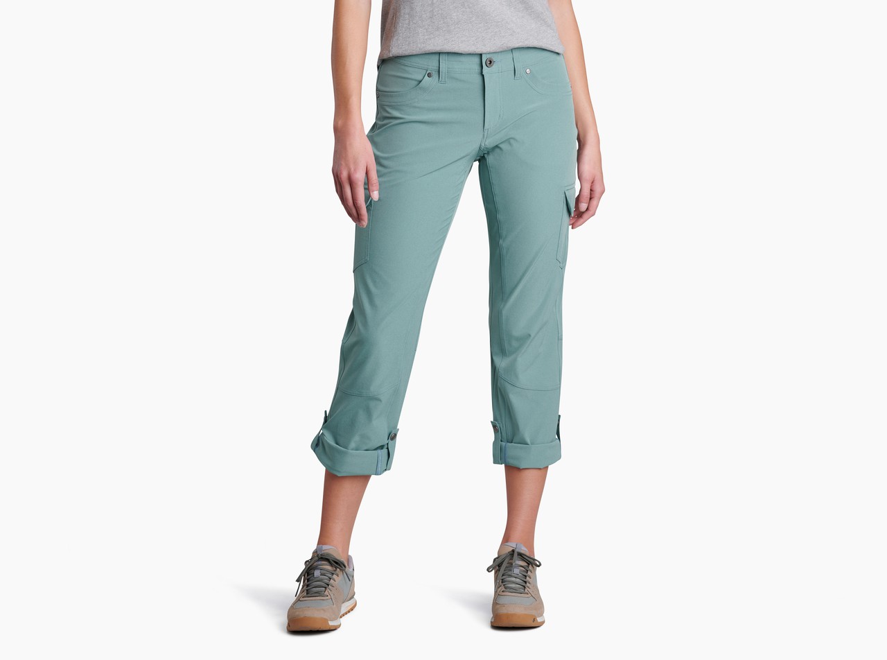 Woman from the waist down wearing Kuhl Freeflex pants in a light teal color with the bottoms rolled up to the knees. 